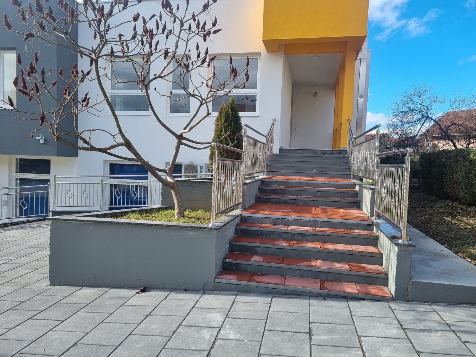 Stepenište sa ogradom od inoksa ispred ulaza u zgradu